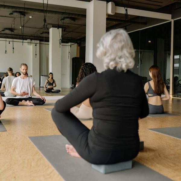 A group of diverse children laughing together while sitting on yoga mats.